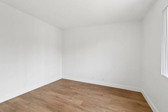 A room with wooden flooring and white walls.