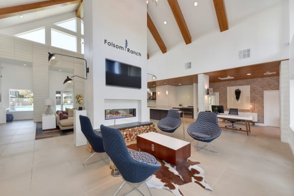 Beautiful Leasing office with blue chairs, cow skinned rug, fireplace with flat screen TV above.  The ceilings are vaulted with wooden beams across..at Folsom Ranch, Folsom, 95630