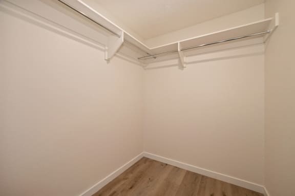 Huge empty closet in bedroom. Closet has shelf above rod where clothing is hung.