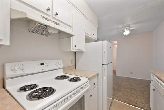 A white stove and refrigerator in a kitchen.
