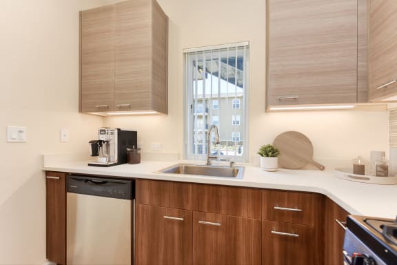 a kitchen with wooden cabinets and a sink and a window  at Addison Ranch Apartments, Petaluma, CA