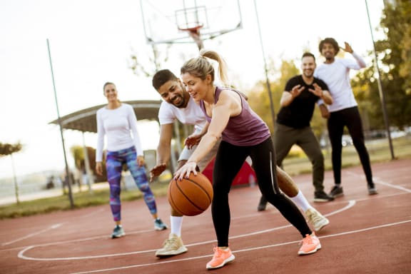 A group of young adults playing basketball at a basketball court.at Fountains of Fair Oaks, California