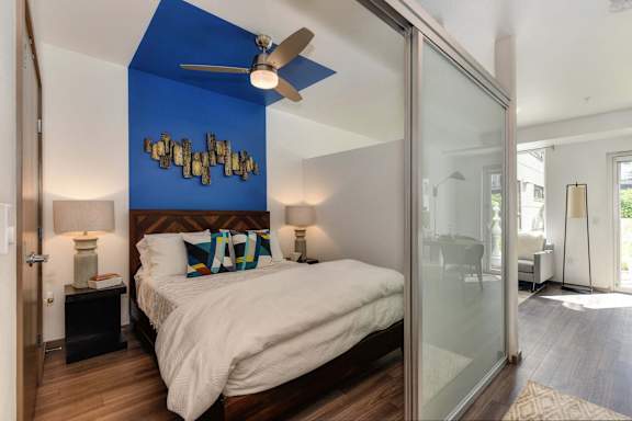 A bedroom with a bed, a ceiling fan, and a wall decoration at Rivet Apartments, Washington