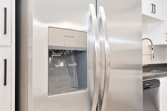 A stainless steel refrigerator with the door open and a drawer visible.