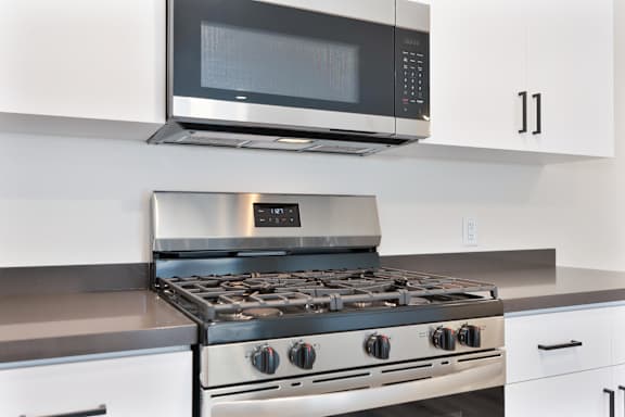A modern kitchen with a stainless steel gas stove and a microwave above it.