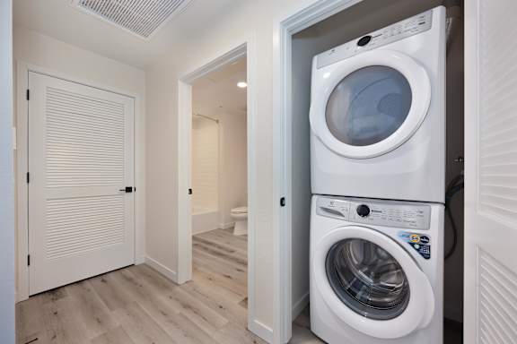 A white washing machine is in a small laundry room.