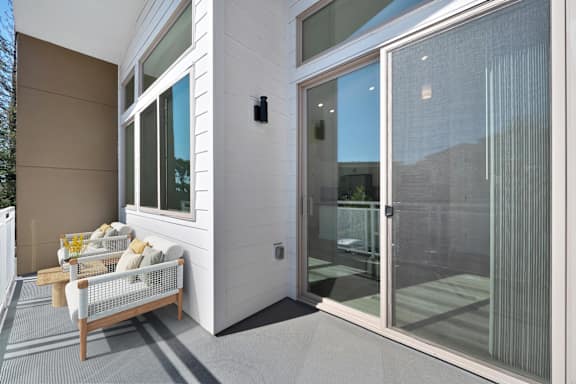 A modern patio with a white couch and a glass door.