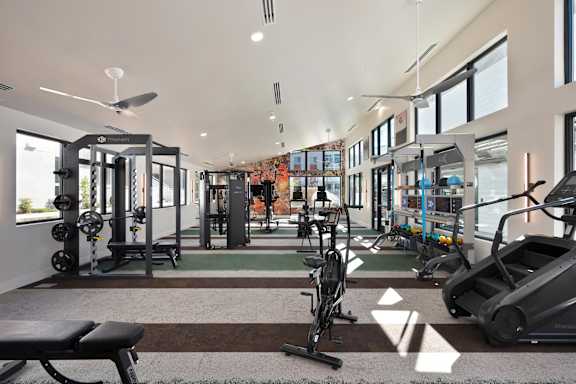 A gym with a variety of equipment including treadmills, weights, and exercise machines.
