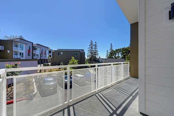 A white fence separates a parking area from a building.