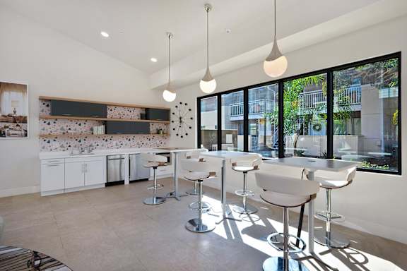 A modern kitchen with white chairs and a bar area.