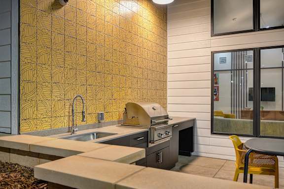 A kitchen with a yellow tiled wall and a stove top oven.