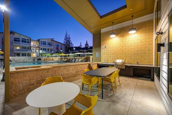 A patio with a table and chairs is lit up at night.