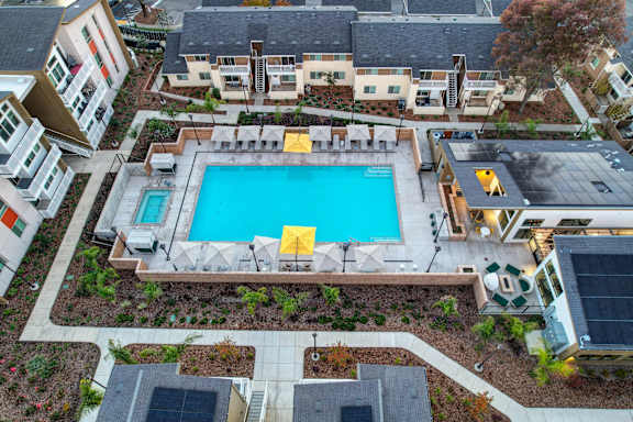 A swimming pool surrounded by a yellow fence and a few chairs.