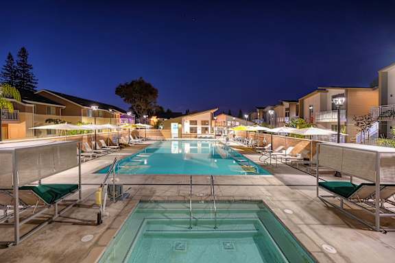 A swimming pool with a waterfall and lounge chairs.