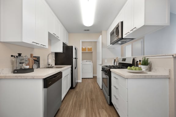 a spacious kitchen with white cabinets and stainless steel appliances