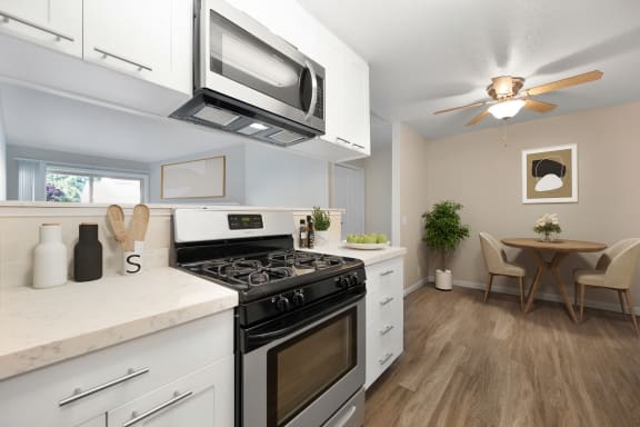 a kitchen with a stove and microwave and a dining room with a table and chairs