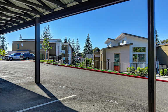 A parking lot with a building and trees in the background.