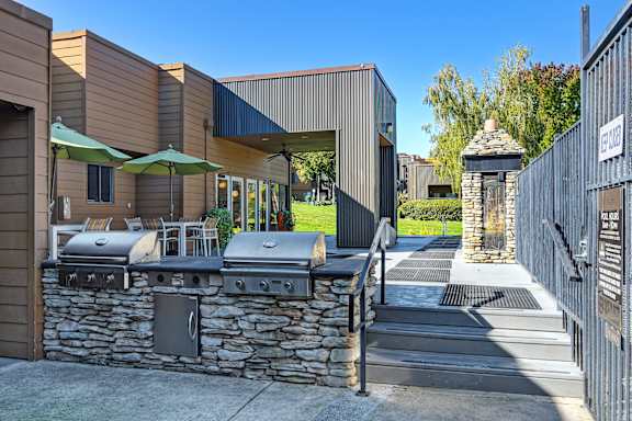 A modern outdoor kitchen area with a stone wall and grills at Fountains of Fair Oaks, Fair Oaks