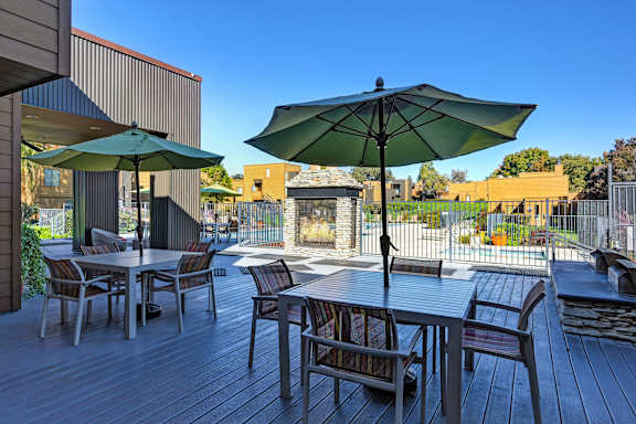 A patio with a table and chairs under an umbrella at Fountains of Fair Oaks, Fair Oaks