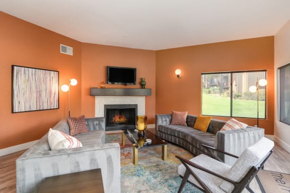 Community Clubhouse area with seating. Two couches available, fireplace and several windows overlooking the property grounds.at Fountains of Fair Oaks, California