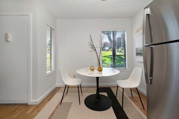 a dining room with a table and chairs and a refrigerator at Fountains of Fair Oaks, Fair Oaks, California