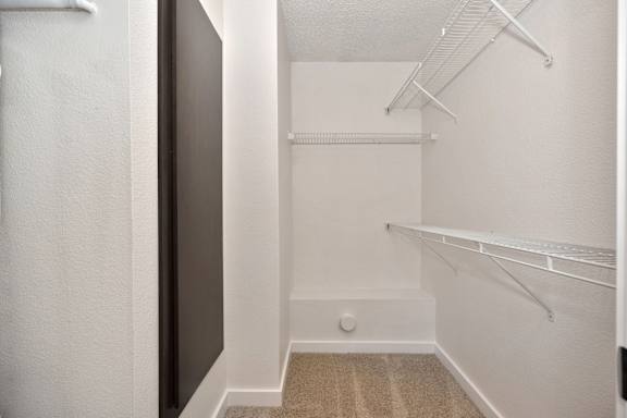 an empty closet with white walls and shelves and a mirrored door at Fountains of Fair Oaks, Fair Oaks