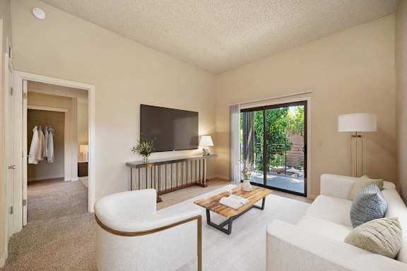 a living room with a couch and a television. Door that leads to private patio and views of the bedroom down the hall. at Fountains of Fair Oaks, Fair Oaks, CA, 95628