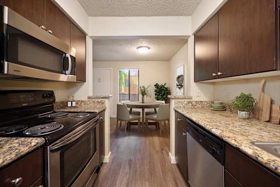 full kitchen with stainless steel appliances and granite counter tops and a dining room table at Fountains of Fair Oaks, California, 95628