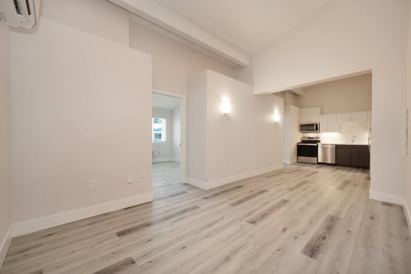 an empty living room and kitchen with white walls and wood flooring  at Track 281 Apartments, Sacramento, CA, 95811