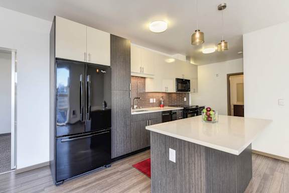 A modern kitchen with a black refrigerator and a white countertop at Rivet Apartments, Seattle, WA 98109
