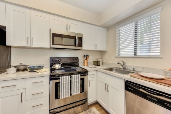 Kitchen with White Cabinets, Oven, Microwave, Window and Dishwasher at Silverstone Apartments, Davis