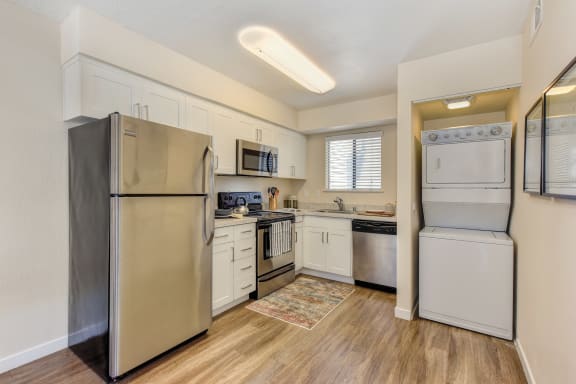 Kitchen with Washer/Dryer , Hardwood Inspired Floor, Refrigerator and White Cabinets at Silverstone Apartments, Davis, CA
