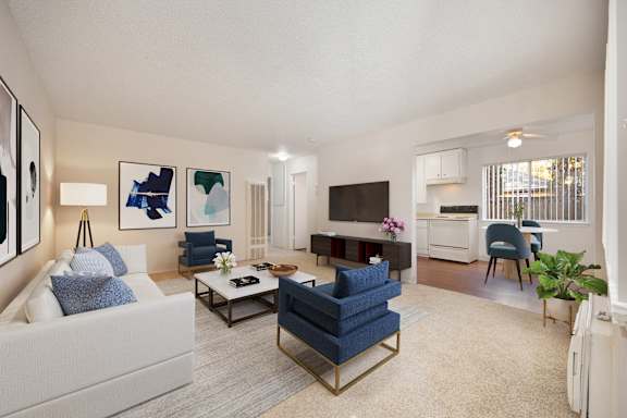 A living room with a white couch, a blue chair, and a television. at Olympus Park Apartments, Roseville, 95661