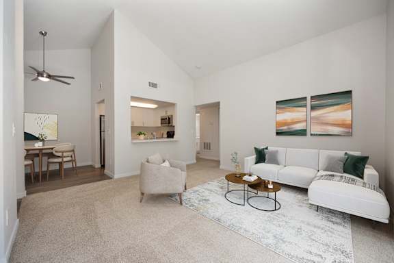 A living room with a white couch, a rug, and a painting on the wall.