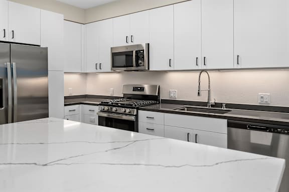 an all white kitchen with stainless steel appliances and white counter tops at Sierra Gateway Apartments, Rocklin