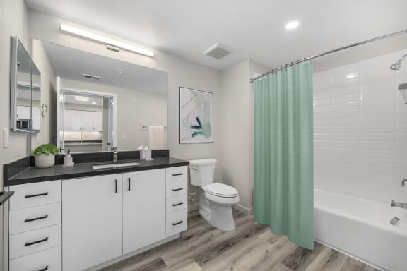 a bathroom with white cabinets and a green shower curtain