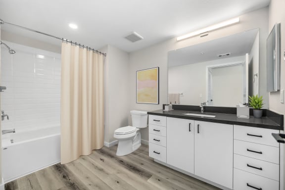 a bathroom with white cabinets and a black countertop at Sierra Gateway Apartments, Rocklin, CA