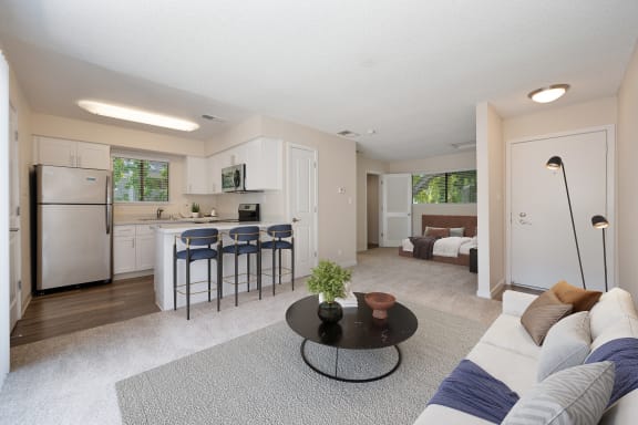 a living room with a couch and a table in front of a kitchen at Silverstone Apartments, Davis, California