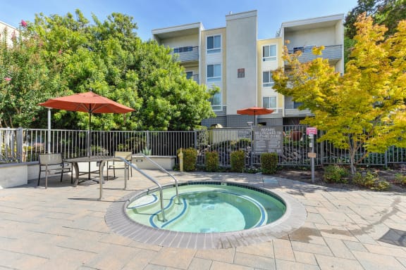 Round in-ground spa on-site.  There are tables, chairs and umbrellas around the pool and spa deck area. at The Retreat at Walnut Creek, Walnut Creek, 94596