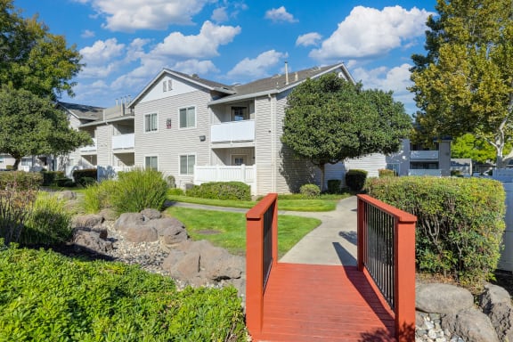 a wooden bridge with a house in the background at The Legacy Apartments, Antelope, California