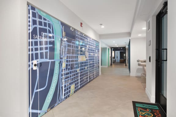 a hallway with a large mural of a city on the wall  at Track 281 Apartments, Sacramento