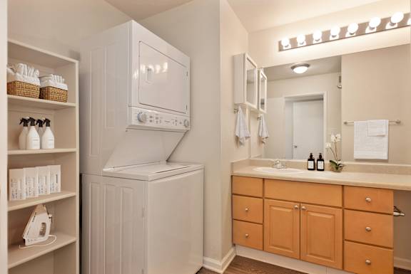 A white microwave oven is mounted above a white cabinet in a bathroom.