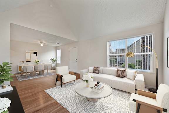 A living room with a white couch, a coffee table, and a dining table with chairs.