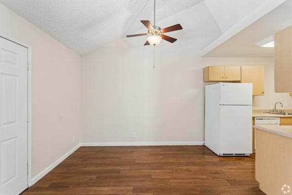 A kitchen with a white refrigerator and wooden floors.