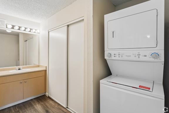 A white dryer is in a bathroom next to a sink.
