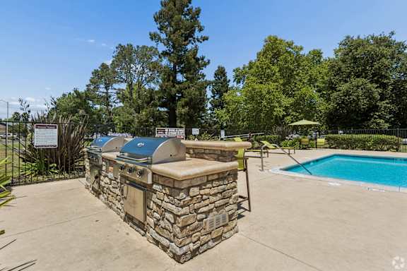 A pool with a stone wall and a hot tub in the middle of a backyard.