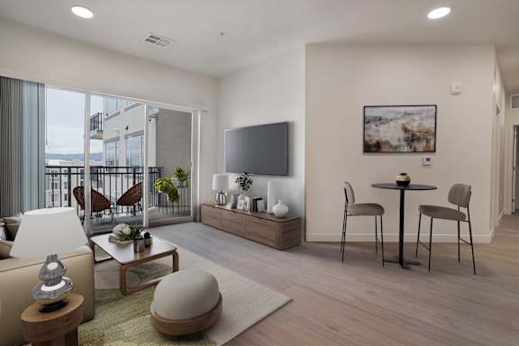 A modern living room with a flat screen TV, a coffee table, and a dining table with chairs.