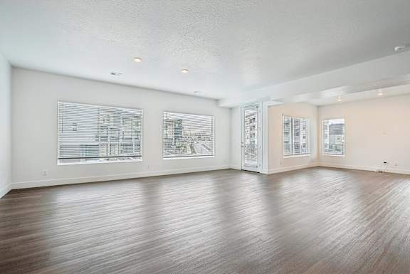 A large empty room with wooden floors and windows.