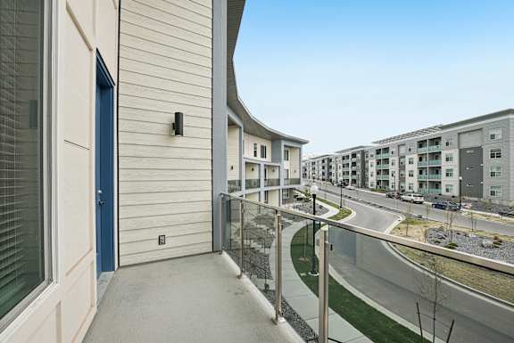 A balcony with a blue door and a glass railing.