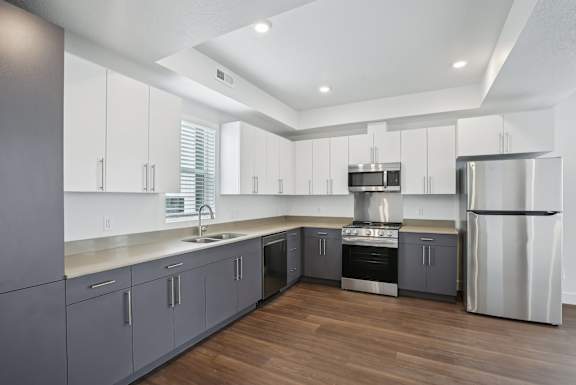 A modern kitchen with wooden floors and stainless steel appliances.